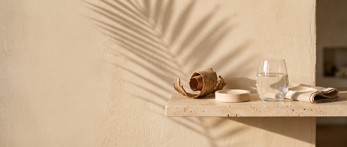 Travertine shelf with tree bark and a glass of water in warm afternoon sunlight